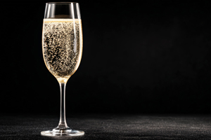 A flute of champagne filled with bubbles against a black background.